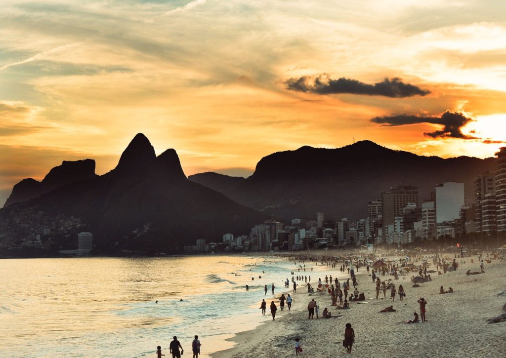 Landscape photo of a Brazilian beach with mountains in the background, at sunset