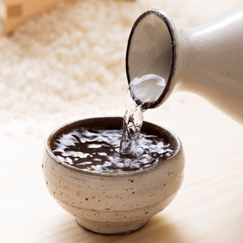 Sake being poured with rice in background